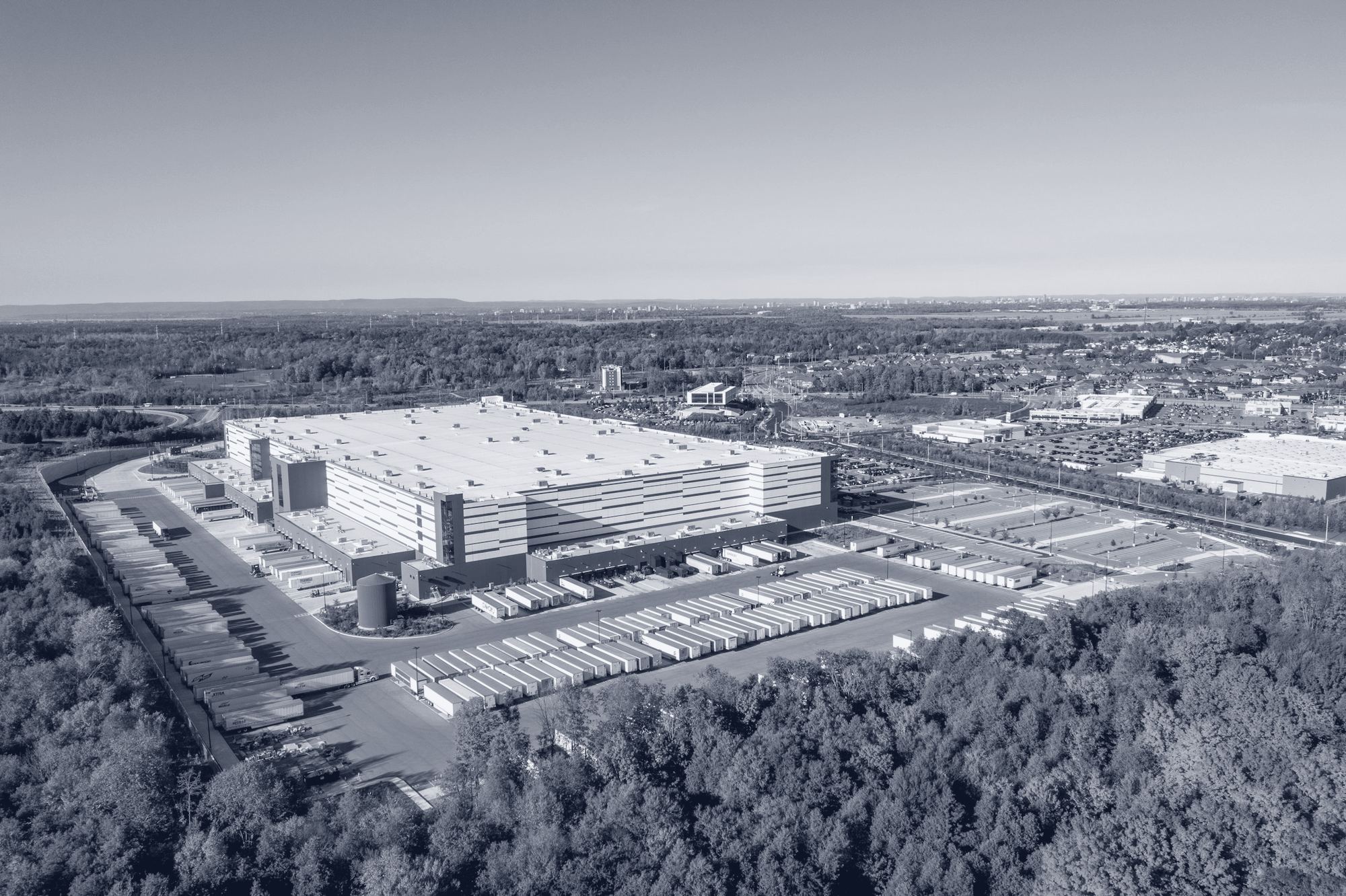 Vista aérea de um parque logístico moderno rodeado de floresta